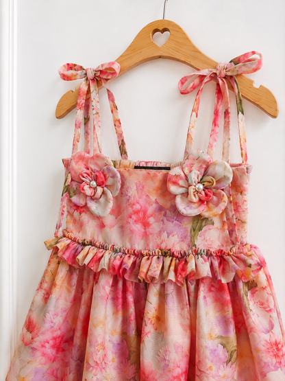 Close up of the Floral dress - handmade 3d flowers, ruffles  detailing, hanging on a wooden hanger against a white background.