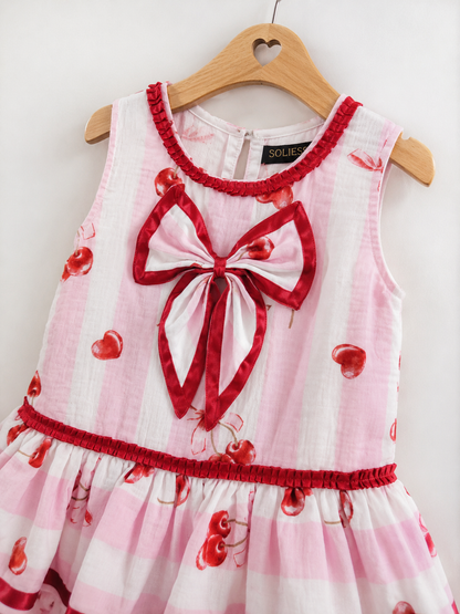 CLOSE UP DETAILING OF THE PINK & WHITE STRIPE CHERRY BOW PRINT DRESS WITH BIG BOW, RED ACCENT RIBBON PLEATING DETAILS.