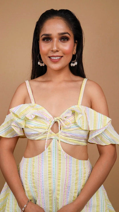 Closeup of the Woman posing against a beige background wearing an offshoulder yellow color striped dress by Soliesse. Its a perfect dress for a sunny day, brunch, date, a vacation or getaway. Its chic & comfortable at the same time.