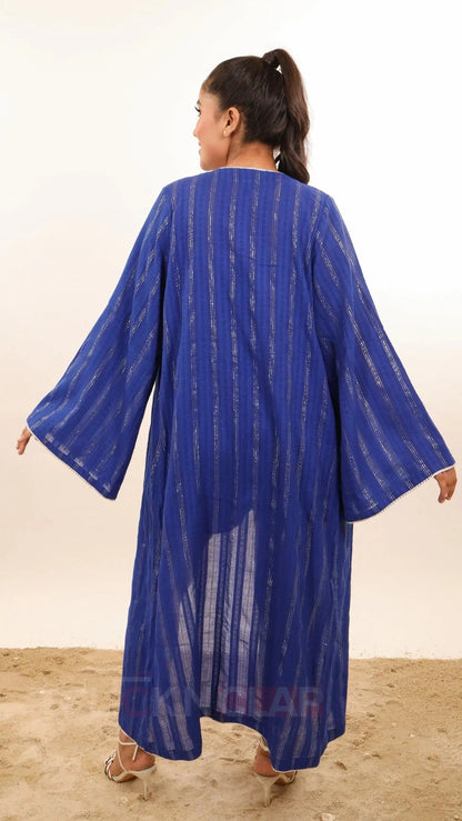 Woman wearing Blue color shrug or open kimono you could say called Nova Kimono by Soliesse brand. Its an open shrug style midi length, fabric is lurex cotton dobby in striped pattern vertical, contrast white pom pom lace detailing, bell sleeves. Can be styled multiple ways, perfect for vacations, getaway or regular summer days or outings.